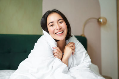 Portrait of young woman lying on bed at home