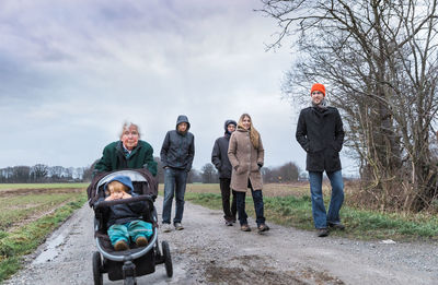 Family on dirt road against sky during winter
