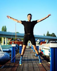 Full length of young man standing against blue sky