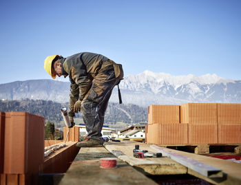 Bricklayer fixing bricks with glue holding caulk gun at construction site