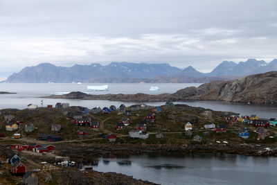 High angle view of houses by sea against mountains in winter