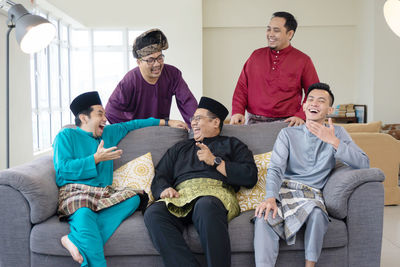 Full length of friends sitting on sofa