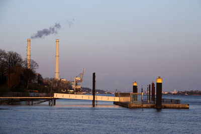 Smoke emitting from factory against sky