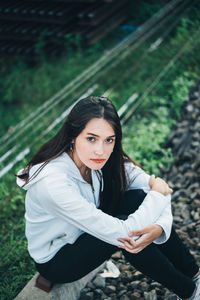 Portrait of young woman sitting on railroad track