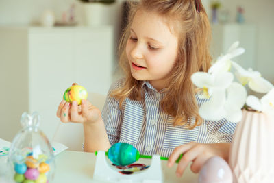 Girl painting easter eggs at table