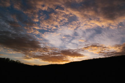 Silhouette of trees against cloudy sky