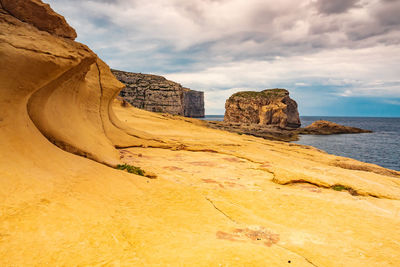 Rock formations by sea against sky