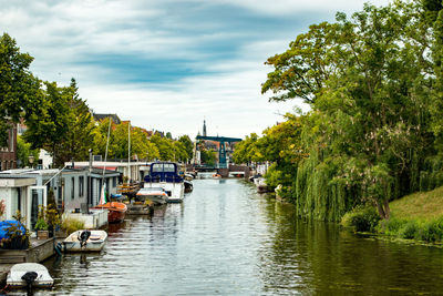 Sailboats moored on river in city against sky