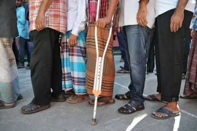 Low section of men waiting in line on footpath