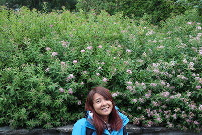 Portrait of smiling woman sitting against plants