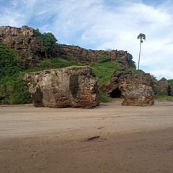 Rock formations on beach against sky