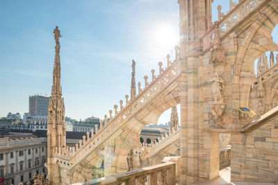 View to spires and statues on roof of duomo through ornate marble fencing. milan, italy