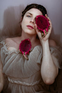 Woman with pitaya in her hand lying in water