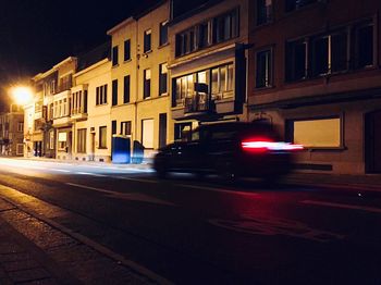 Blurred motion of car on street against buildings at night