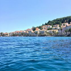 Houses in calm sea against blue sky