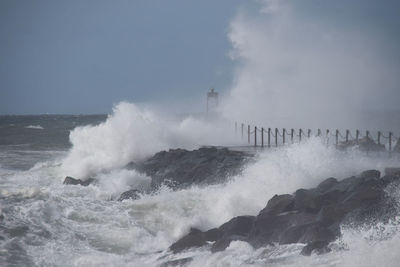 Waves splashing on rocks against sky