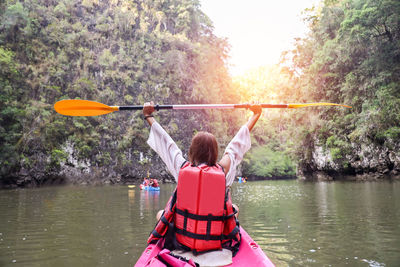 Woman holding oar while sitting on boat in river