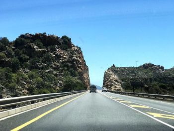 Road leading towards mountain against clear sky