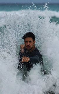 Portrait of shirtless man surfing in sea