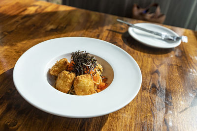 Fusion spaghetti topped with ebiko and seaweed attached with fried breaded meat. in a white plate.