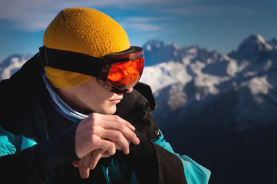 Portrait in profile of a male skier on a mountain, against the backdrop of snow-capped mountains and