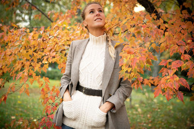 Portrait of young woman standing against plants