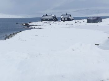 Snow covered land by building against sky