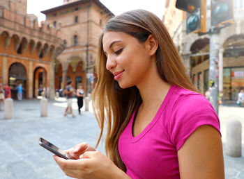 Young woman using mobile phone in city