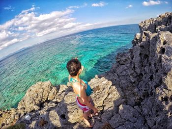 Woman on rock in sea against sky