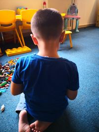 Rear view of boy sitting on table at home
