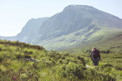 Rear view of man walking on mountain against sky