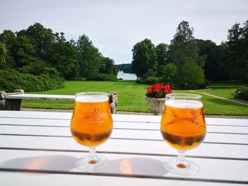 Close-up of beer glass on table against sky