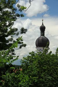 Low angle view of trees against cloudy sky