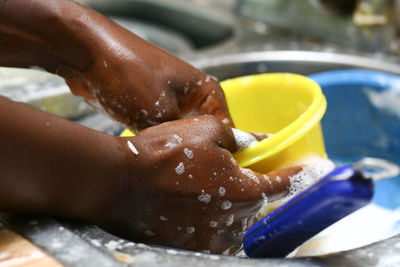 Cropped hands of person washing utensils