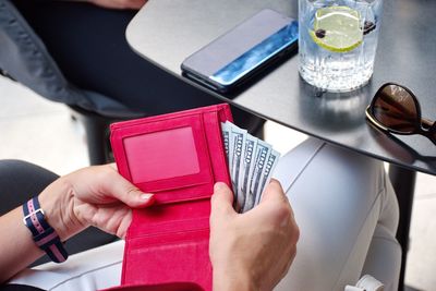 Cropped image of woman putting paper currency into wallet