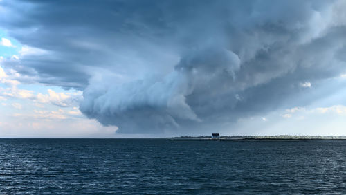 Scenic view of sea against sky, tornado forming on a small island