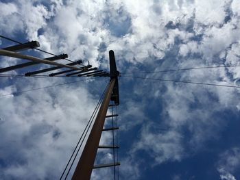 Low angle view of cranes against cloudy sky