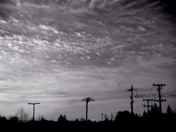 Silhouette of electricity pylon against dramatic sky