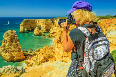 Woman photographing sea against sky