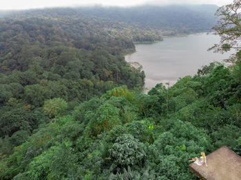 Woman sitting at observation point against lake in forest