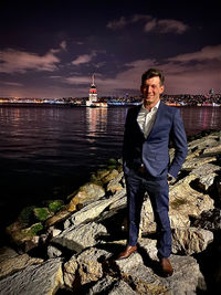 Portrait of man standing on rock against sky at night