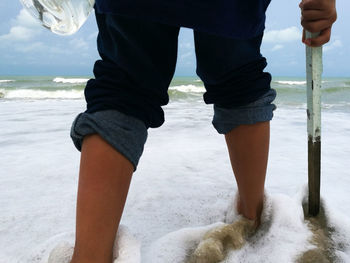 Low section of man standing on beach