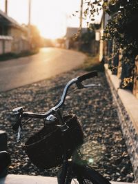 Close-up of bicycle on road during sunset