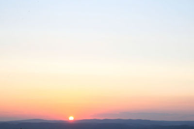 Scenic view of silhouette mountains against orange sky