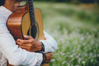 Midsection of man holding guitar in park