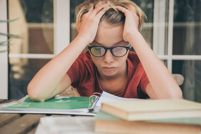 Tired student doing homework at home sitting outdoor with school books and newspaper. boy weary