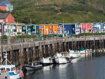 Boats moored in canal by houses in city