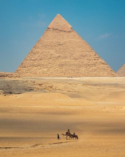 People riding horse in desert against sky