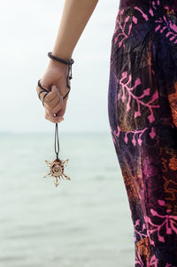 Midsection of man holding necklace from sea shell