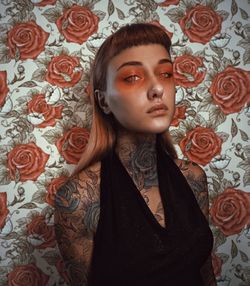 Portrait of woman with tattoo on body against wall